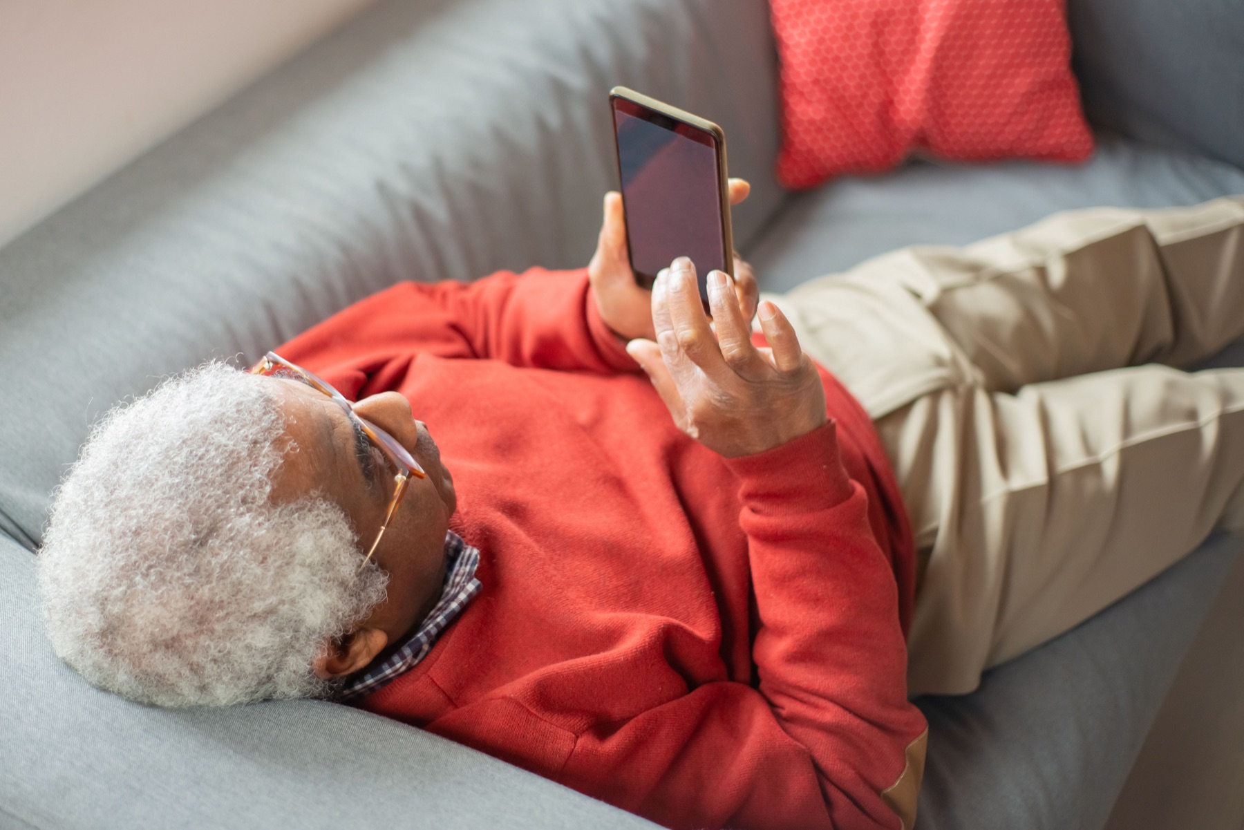 An older adult using a phone comfortably at home